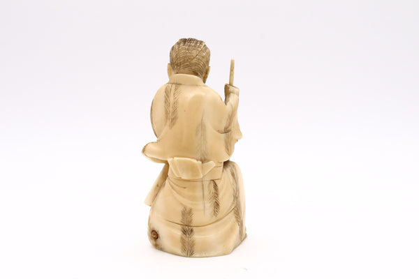 JAPAN 1900 MEIJI PERIOD CARVED NETSUKE OF A SEATED AND DRESSED STONE CARVER