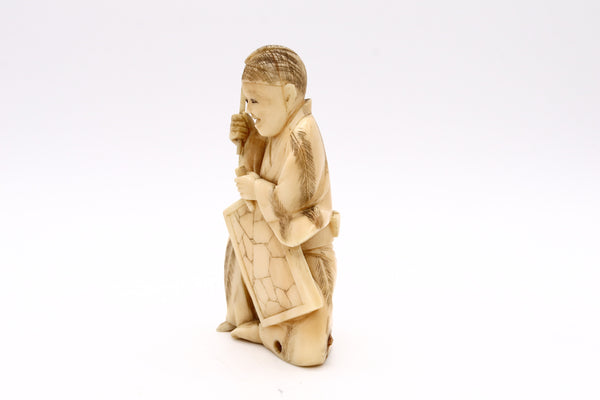 JAPAN 1900 MEIJI PERIOD CARVED NETSUKE OF A SEATED AND DRESSED STONE CARVER
